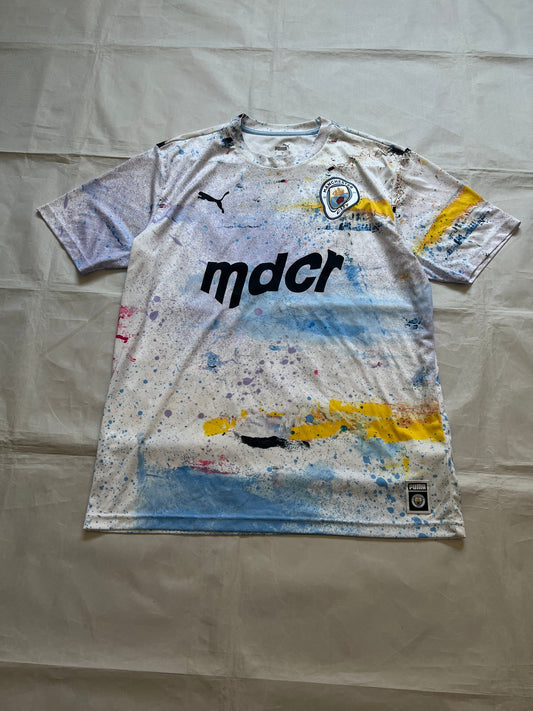 Puma blue and white football jersey with Manchester City crest and splatter paint design.