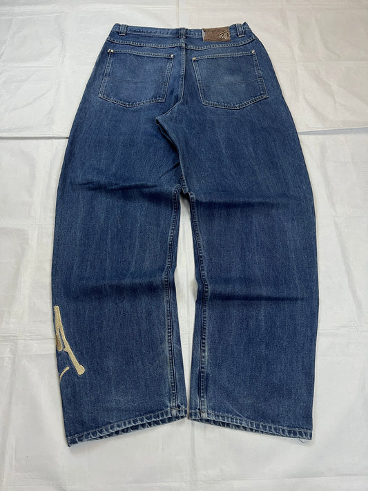 Johnny Blaze blue wide leg jeans with embroidered logo and leather patch on waistband.