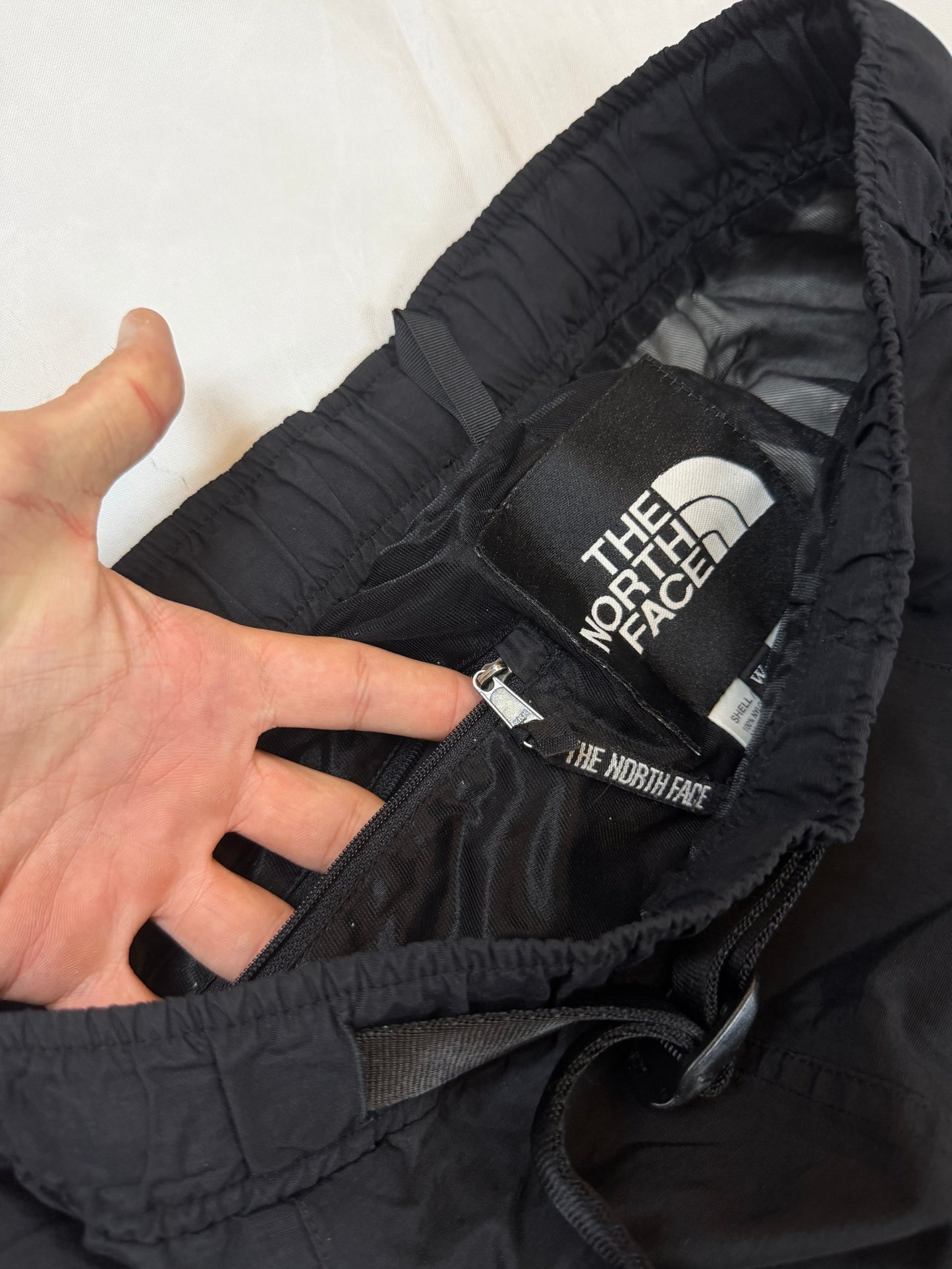 The North Face black hiking trousers with embroidered logo and adjustable Velcro ankle closures.