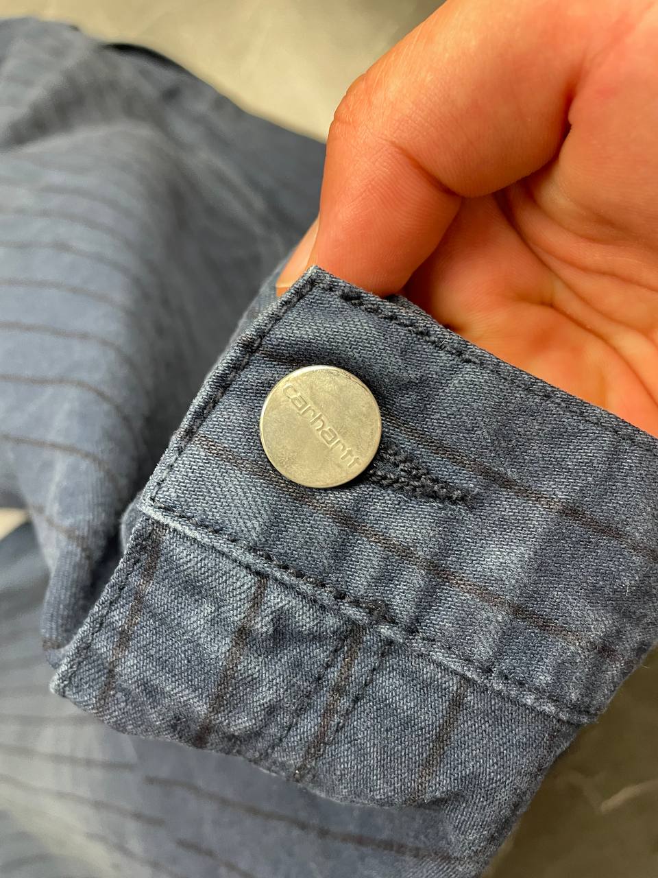 Carhartt navy shorts with pinstripe pattern, utility pockets, and branded metal button.
