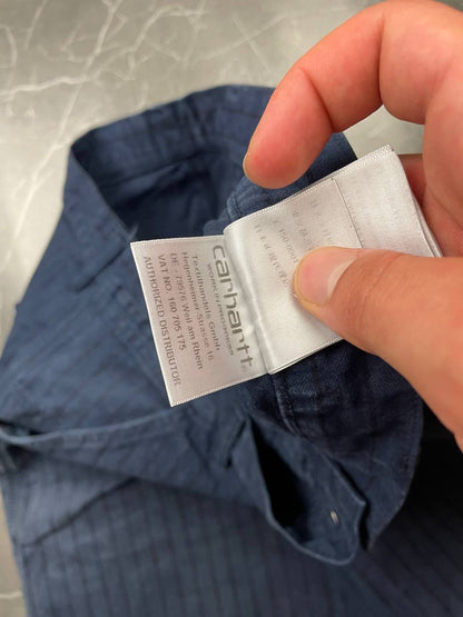Carhartt navy shorts with pinstripe pattern, utility pockets, and branded metal button.