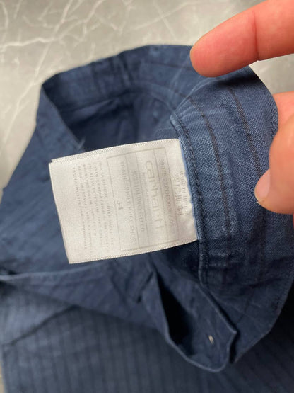 Carhartt navy shorts with pinstripe pattern, utility pockets, and branded metal button.
