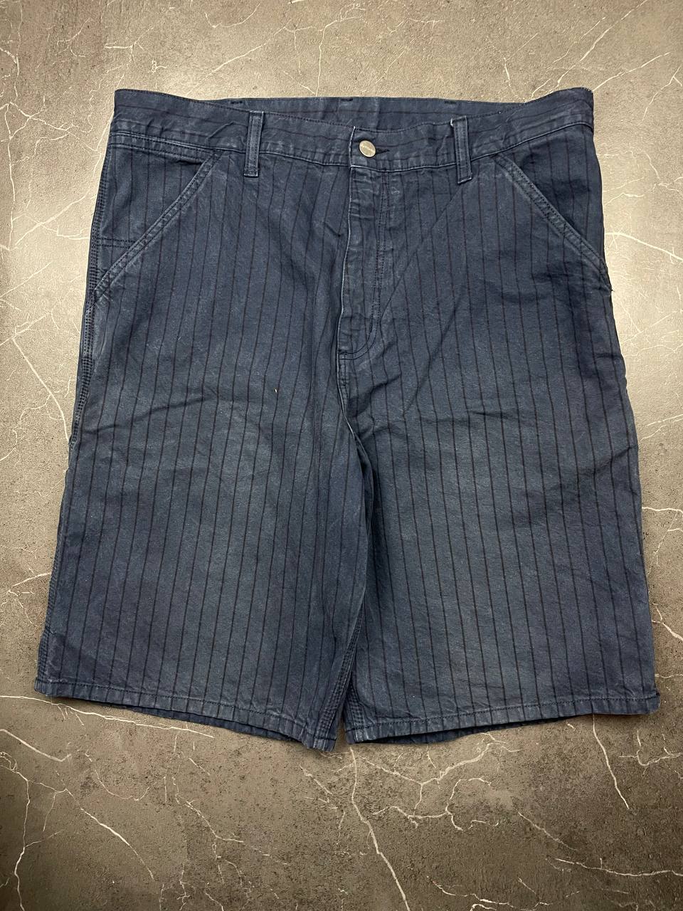 Carhartt navy shorts with pinstripe pattern, utility pockets, and branded metal button.