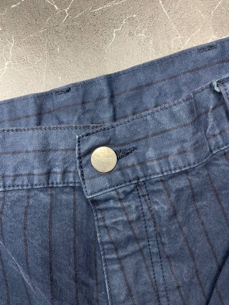 Carhartt navy shorts with pinstripe pattern, utility pockets, and branded metal button.