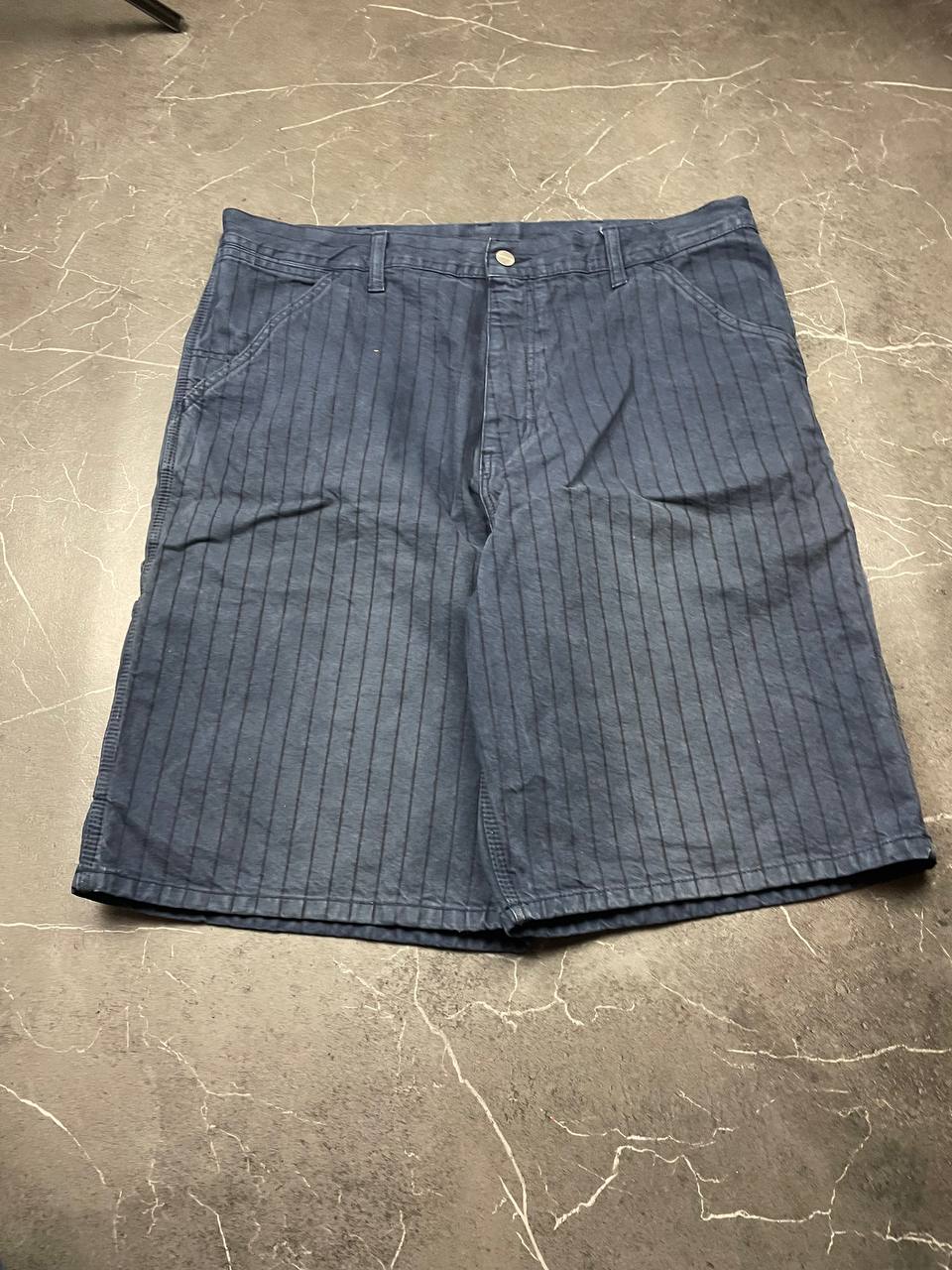 Carhartt navy shorts with pinstripe pattern, utility pockets, and branded metal button.