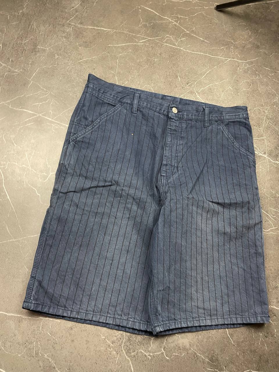 Carhartt navy shorts with pinstripe pattern, utility pockets, and branded metal button.