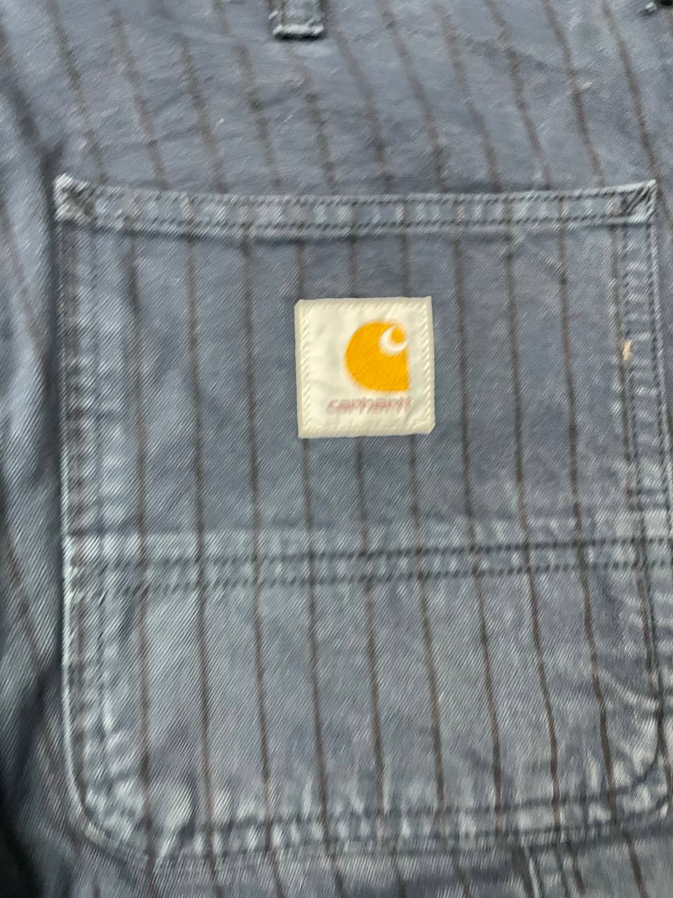 Carhartt navy shorts with pinstripe pattern, utility pockets, and branded metal button.