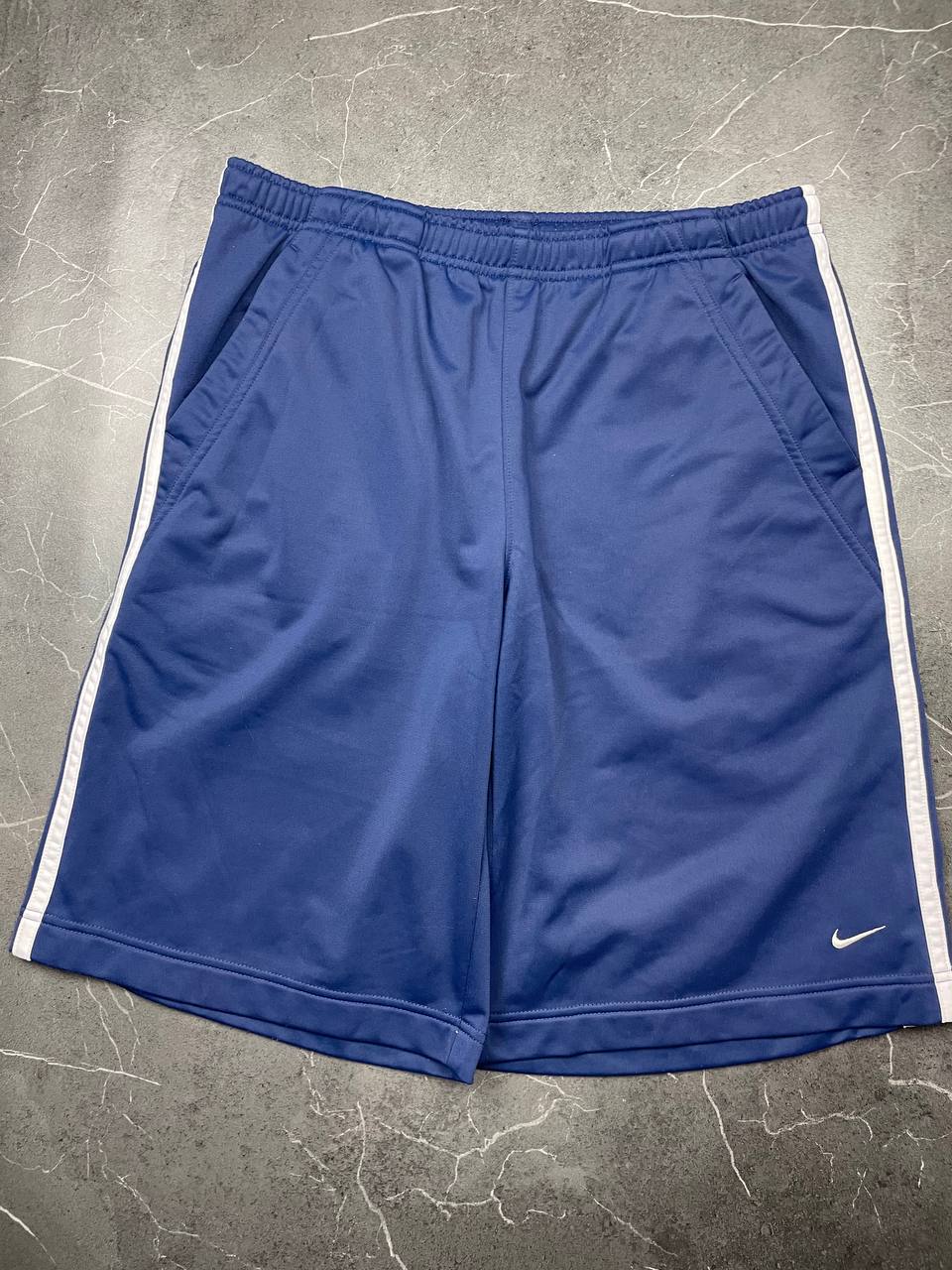 Nike blue sports shorts with white side stripes and small swoosh logo, zip pocket.
