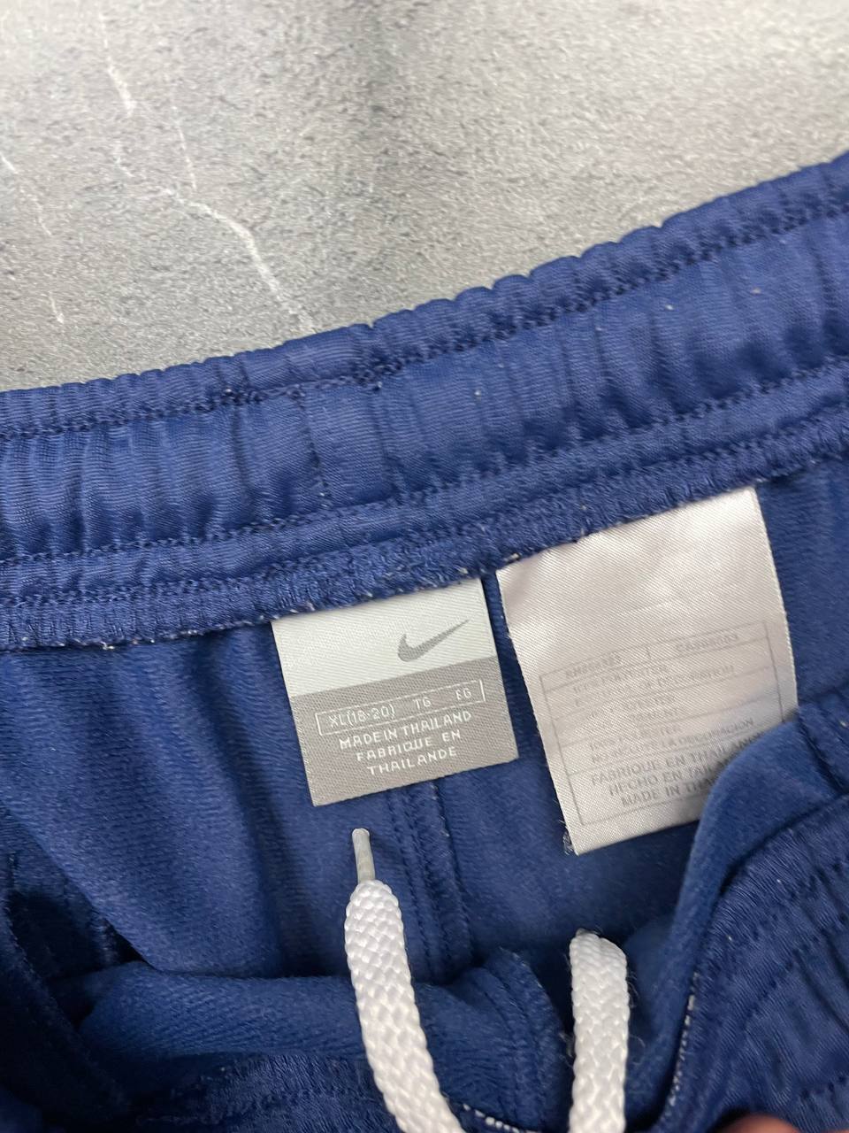 Nike blue sports shorts with white side stripes and small swoosh logo, zip pocket.