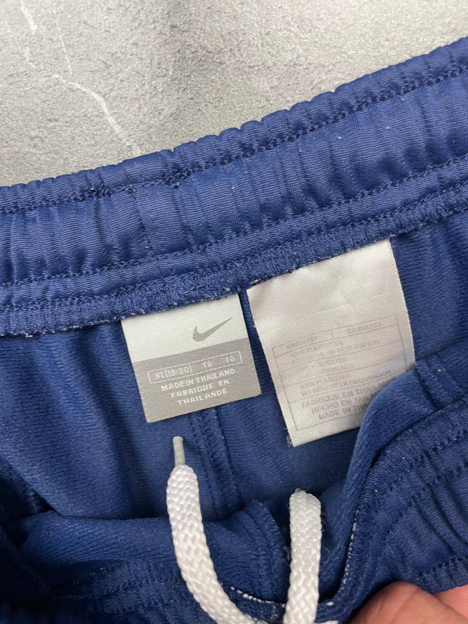 Nike blue sports shorts with white side stripes and small swoosh logo, zip pocket.
