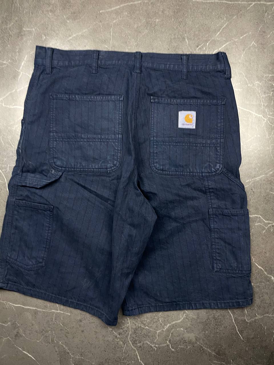 Carhartt navy shorts with pinstripe detail and logo patch on back pocket.
