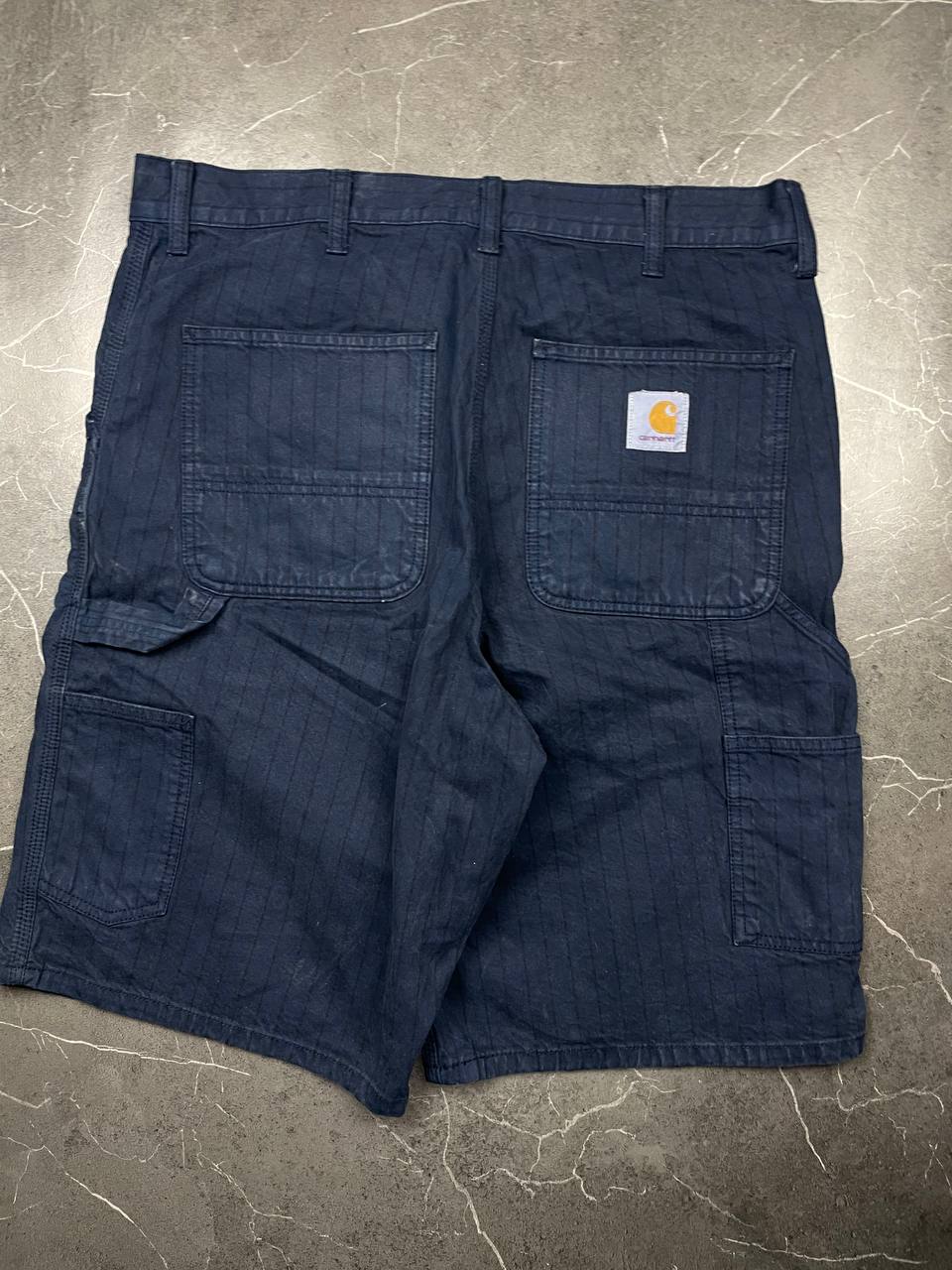 Carhartt navy shorts with pinstripe detail and logo patch on back pocket.