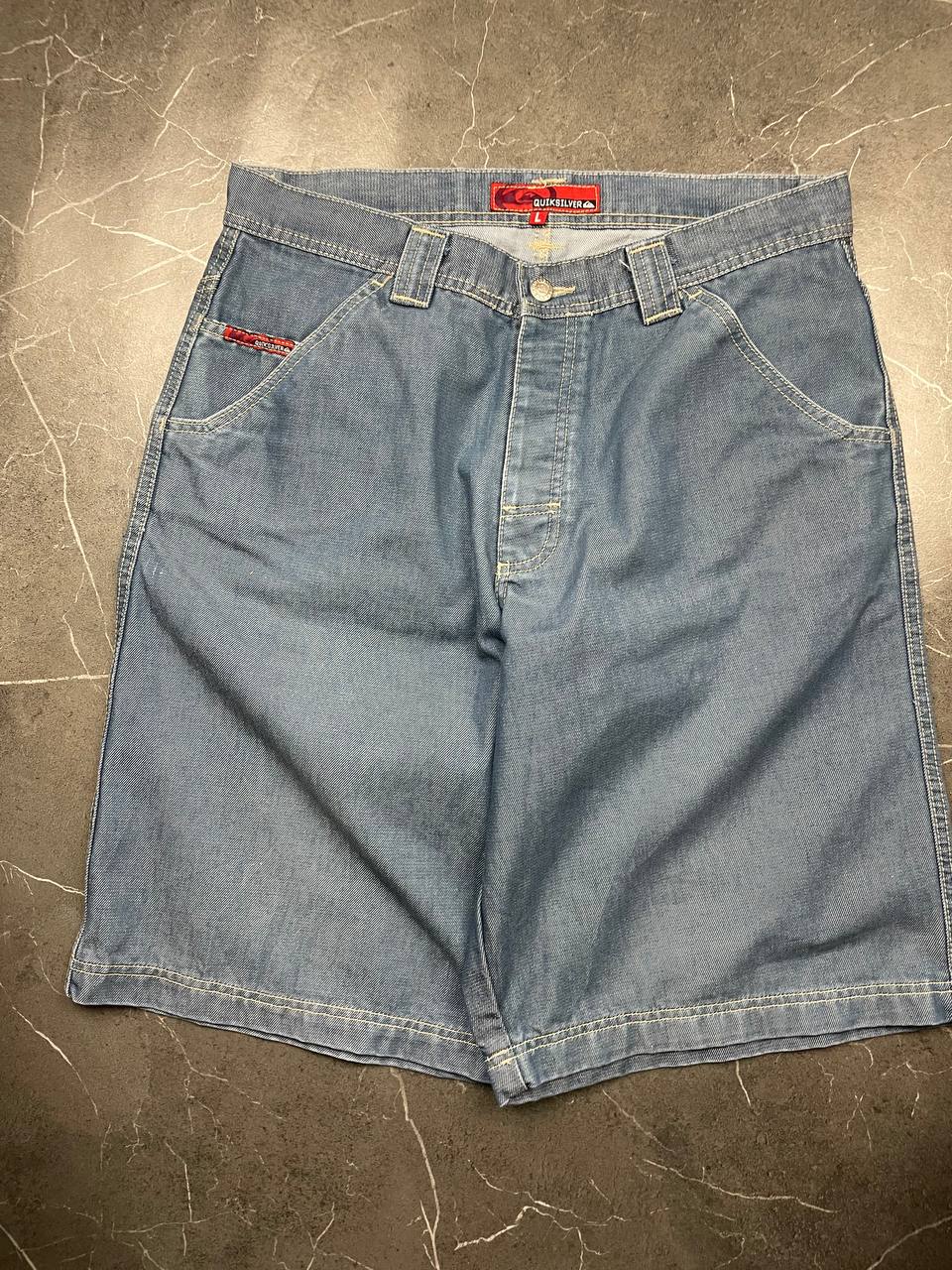 Quiksilver blue denim shorts with yellow contrast stitching and red logo patch.