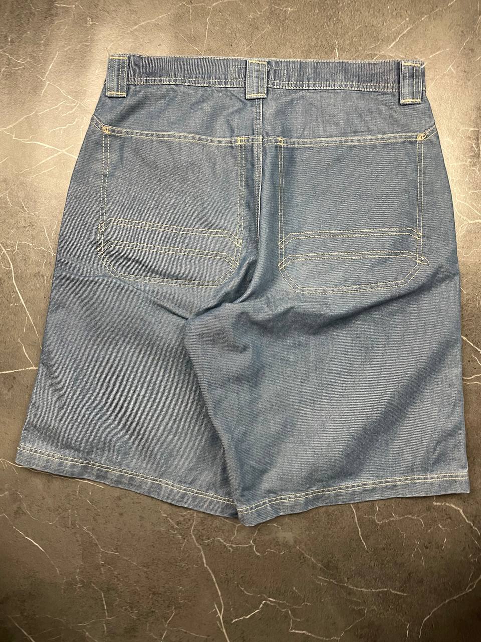 Quiksilver blue denim shorts with yellow contrast stitching and red logo patch.