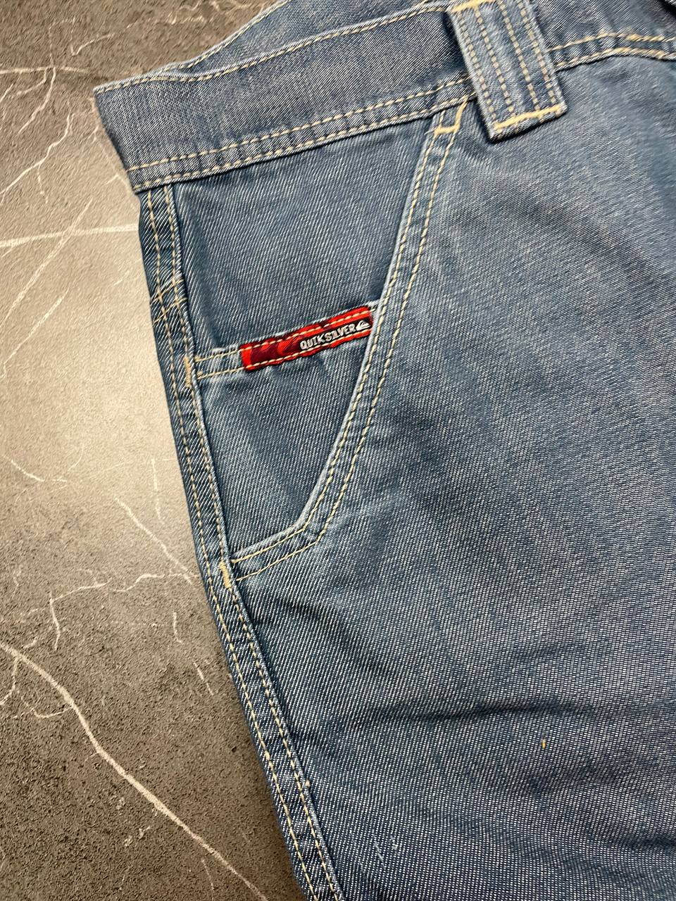 Quiksilver blue denim shorts with yellow contrast stitching and red logo patch.
