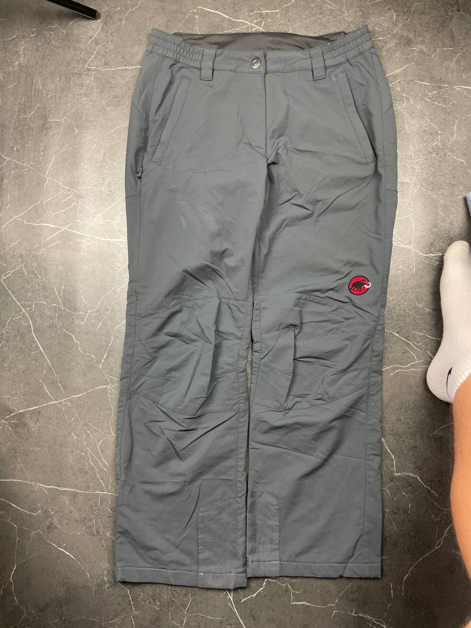 Mammut grey softshell outdoor trousers with reinforced knees, elastic waistband, and zipped pockets.