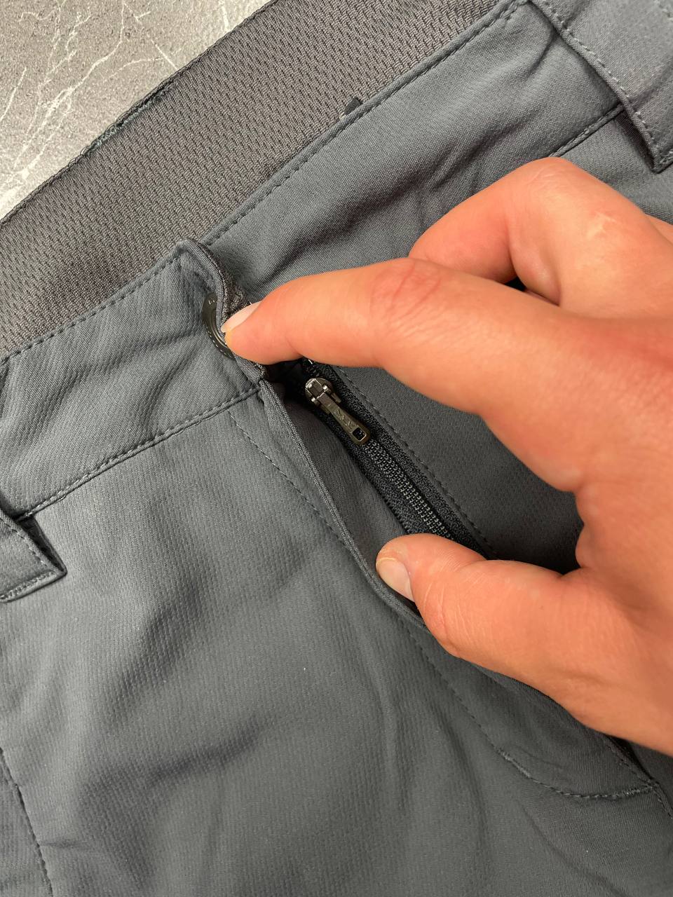 Mammut grey softshell outdoor trousers with reinforced knees, elastic waistband, and zipped pockets.