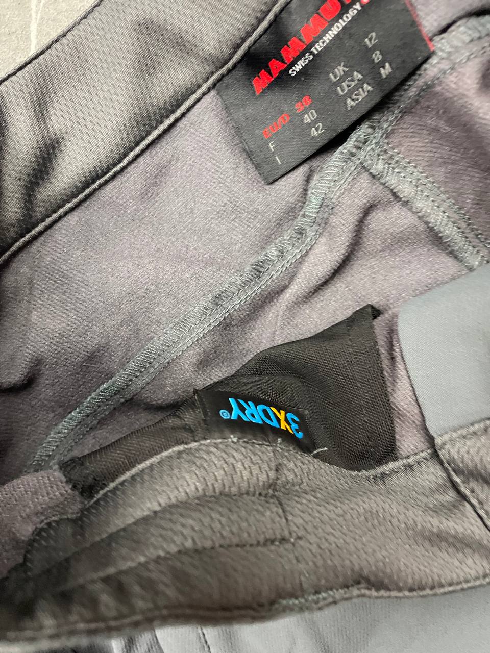 Mammut grey softshell outdoor trousers with reinforced knees, elastic waistband, and zipped pockets.