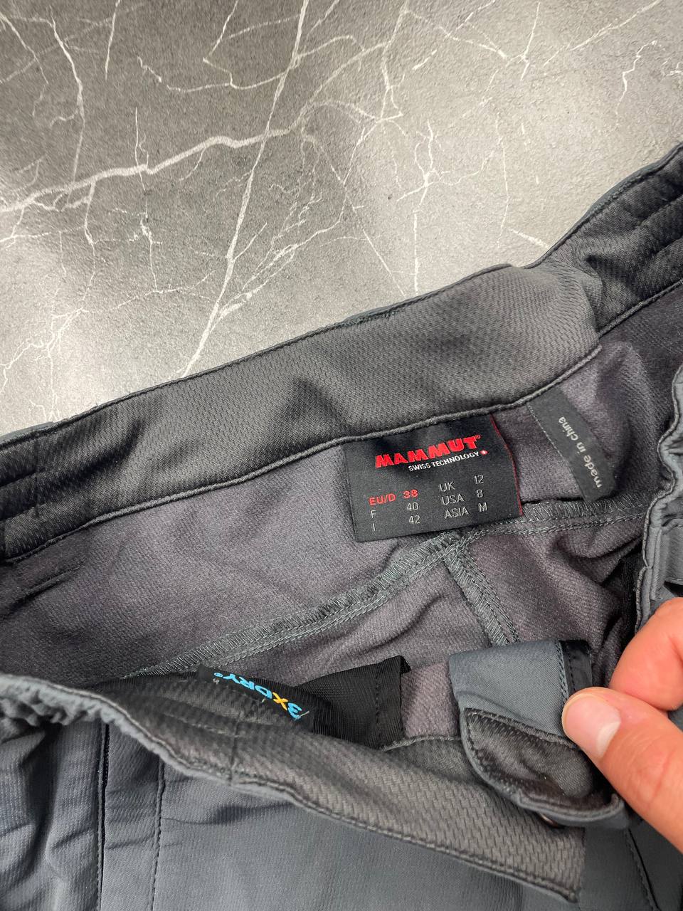 Mammut grey softshell outdoor trousers with reinforced knees, elastic waistband, and zipped pockets.