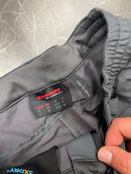 Mammut grey softshell outdoor trousers with reinforced knees, elastic waistband, and zipped pockets.
