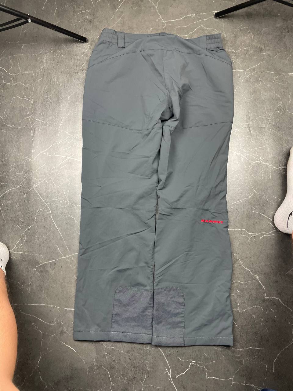 Mammut grey softshell outdoor trousers with reinforced knees, elastic waistband, and zipped pockets.