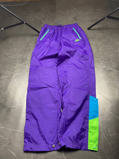 Nike track pants purple with blue and green accents, nylon material, elastic waistband.