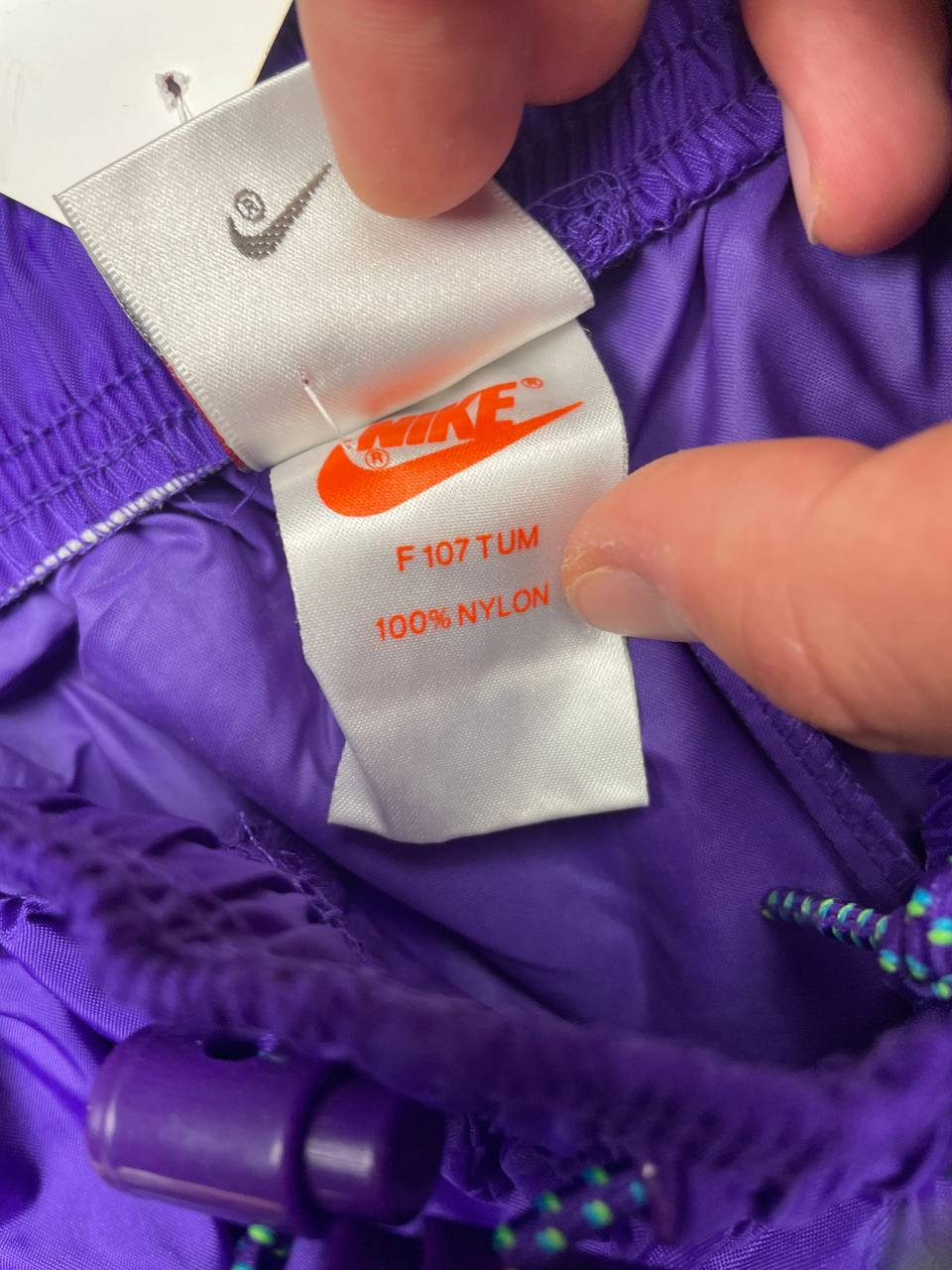 Nike track pants purple with blue and green accents, nylon material, elastic waistband.