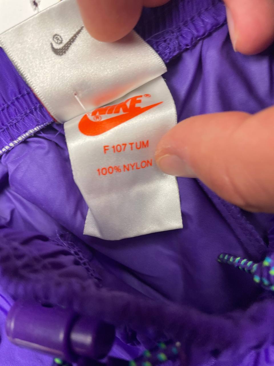 Nike track pants purple with blue and green accents, nylon material, elastic waistband.