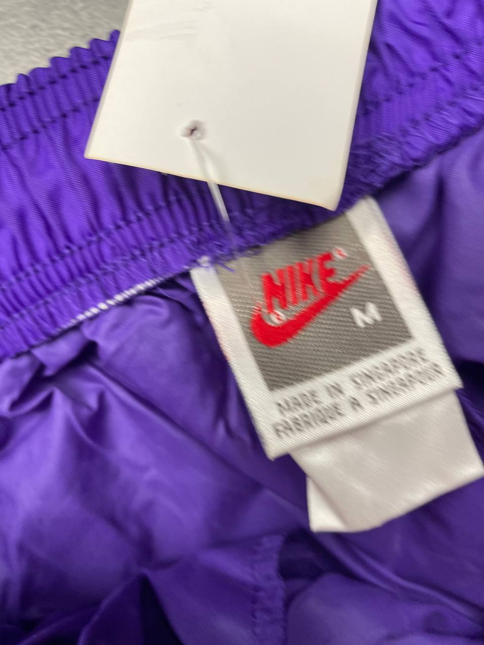 Nike track pants purple with blue and green accents, nylon material, elastic waistband.