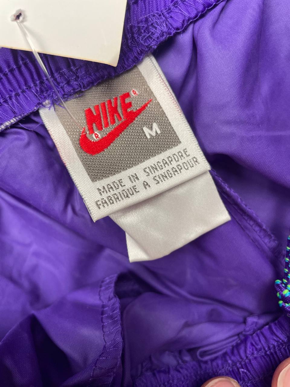 Nike track pants purple with blue and green accents, nylon material, elastic waistband.