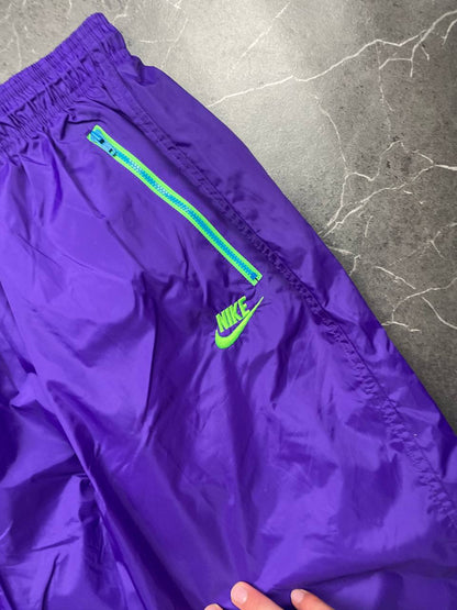 Nike track pants purple with blue and green accents, nylon material, elastic waistband.