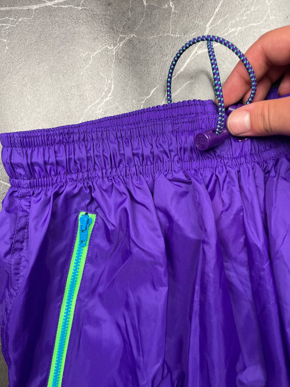 Nike track pants purple with blue and green accents, nylon material, elastic waistband.