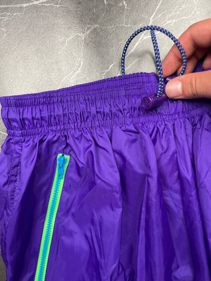 Nike track pants purple with blue and green accents, nylon material, elastic waistband.