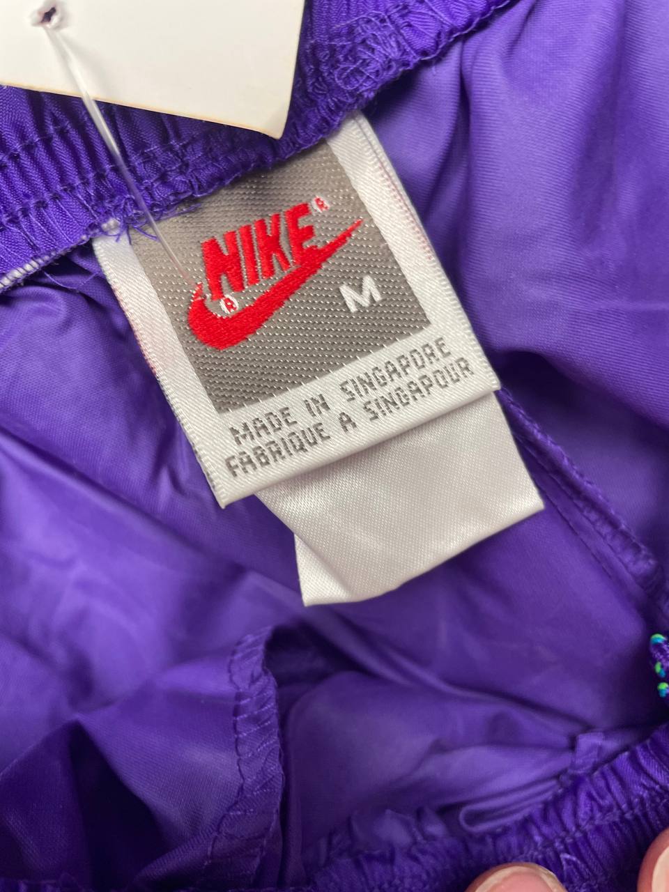 Nike track pants purple with blue and green accents, nylon material, elastic waistband.