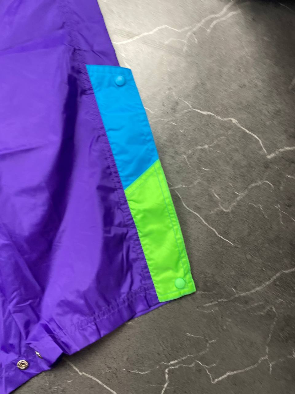 Nike track pants purple with blue and green accents, nylon material, elastic waistband.