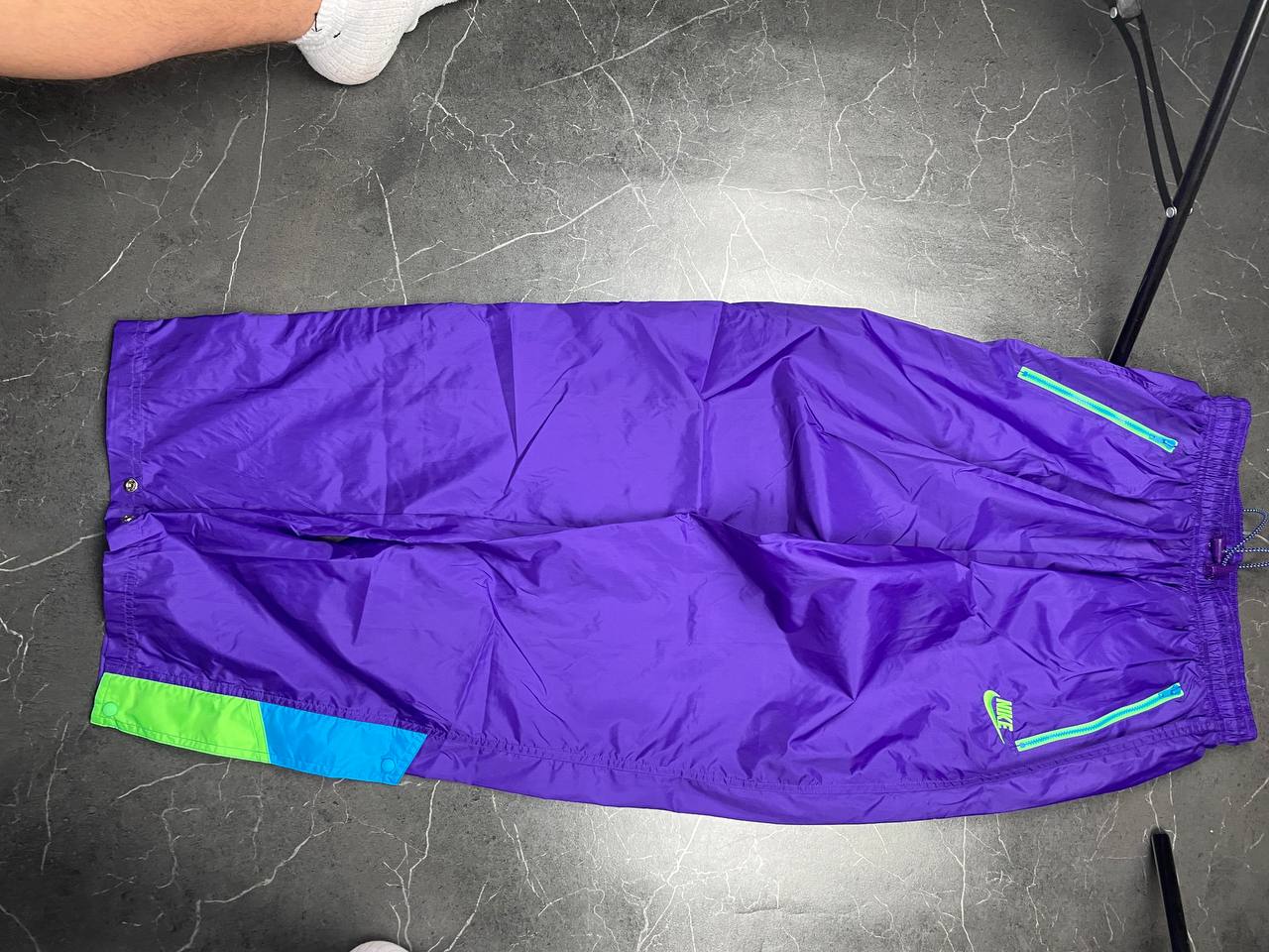 Nike track pants purple with blue and green accents, nylon material, elastic waistband.