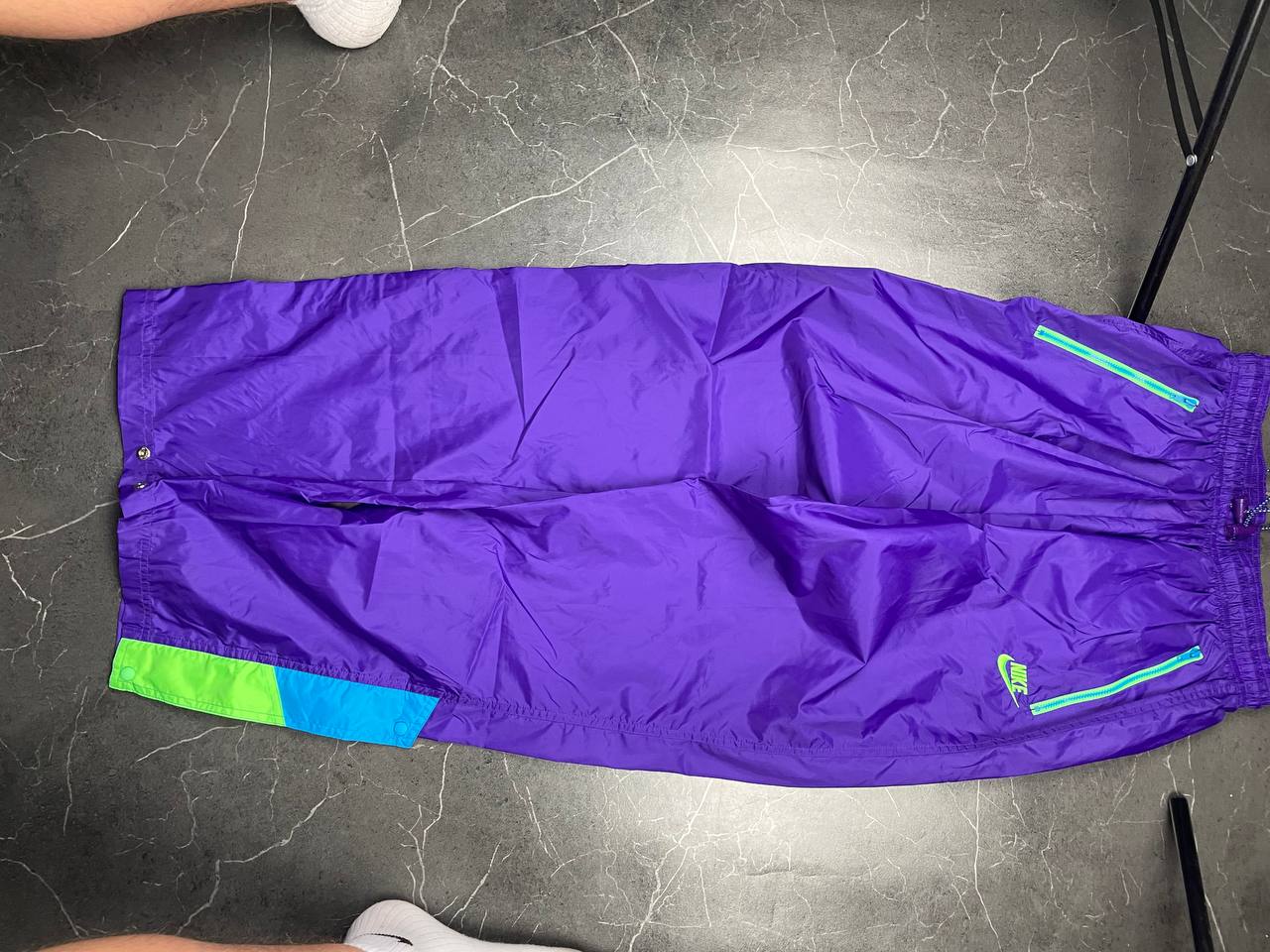 Nike track pants purple with blue and green accents, nylon material, elastic waistband.
