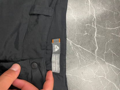 Nike black ACG outdoor pants, waterproof nylon, zip and button closure, zipped side pockets.