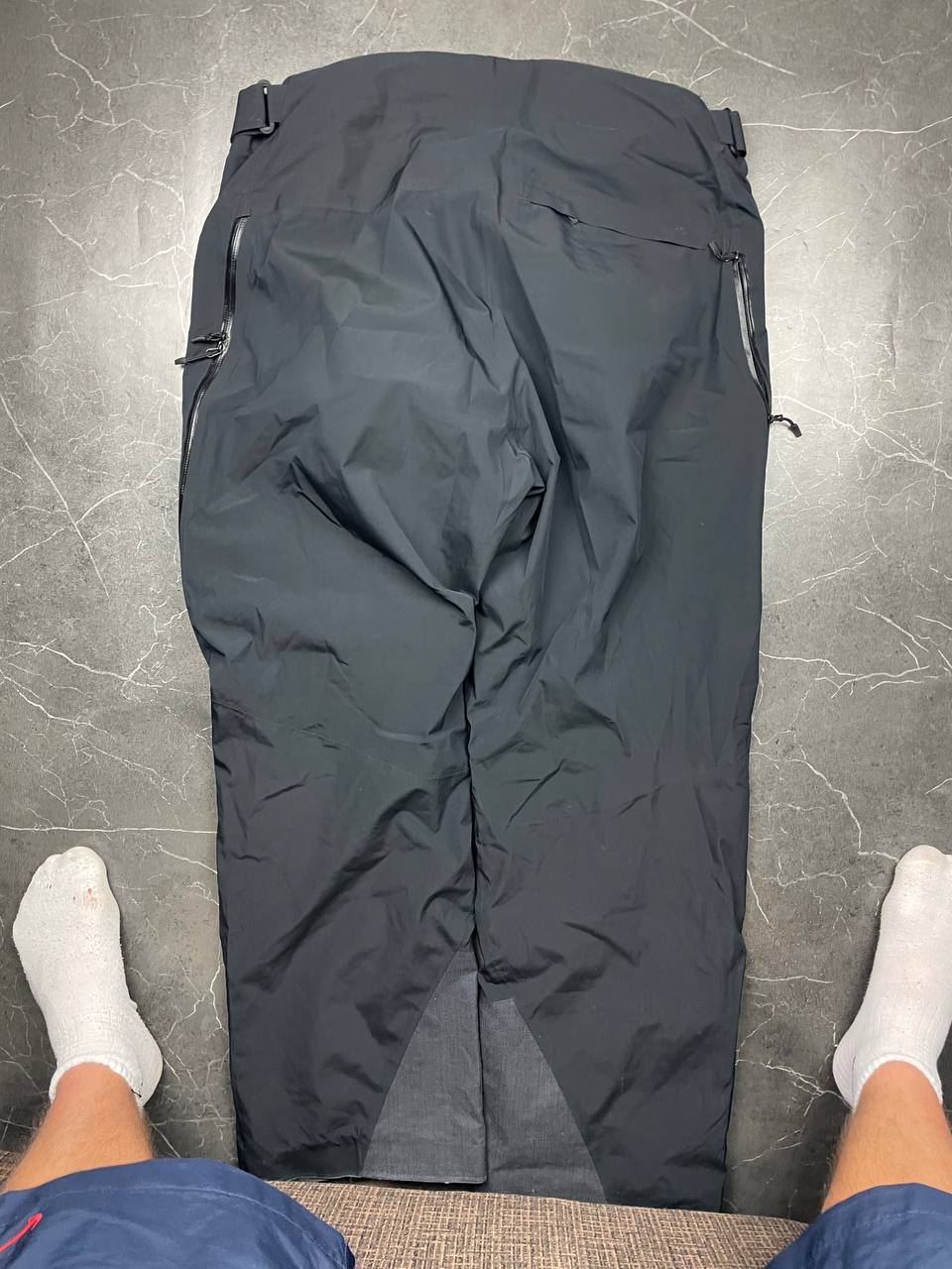 Haglöfs black softshell outdoor trousers with zipped pockets and adjustable Velcro waist tabs.