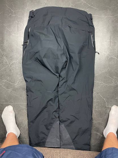 Haglöfs black softshell outdoor trousers with zipped pockets and adjustable Velcro waist tabs.