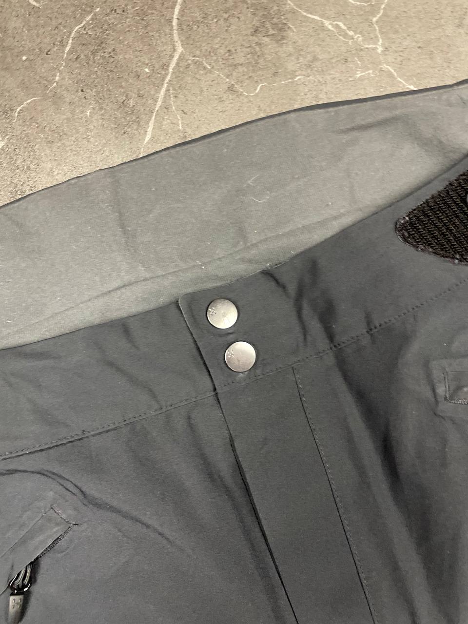 Haglöfs black softshell outdoor trousers with zipped pockets and adjustable Velcro waist tabs.