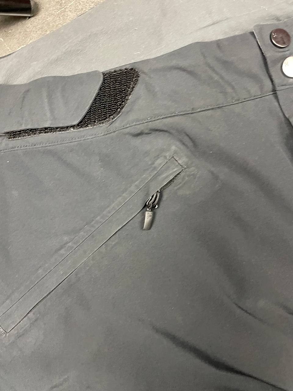 Haglöfs black softshell outdoor trousers with zipped pockets and adjustable Velcro waist tabs.
