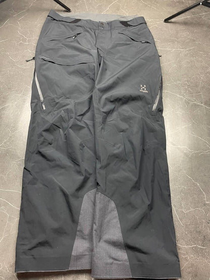 Haglöfs black softshell outdoor trousers with zipped pockets and adjustable Velcro waist tabs.