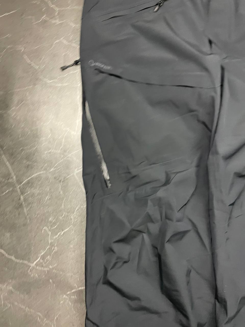Haglöfs black softshell outdoor trousers with zipped pockets and adjustable Velcro waist tabs.
