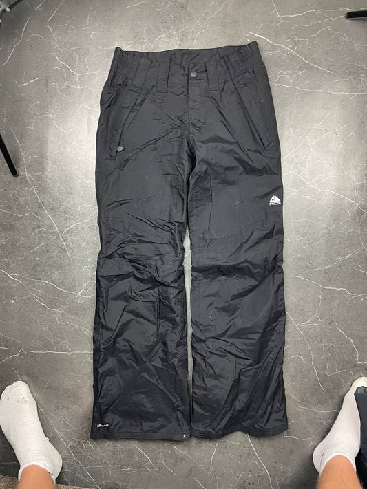 Nike black ski trousers with ACG branding, button closure, and elasticated waistband.
