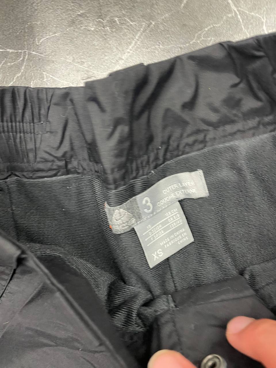 Nike black ski trousers with ACG branding, button closure, and elasticated waistband.