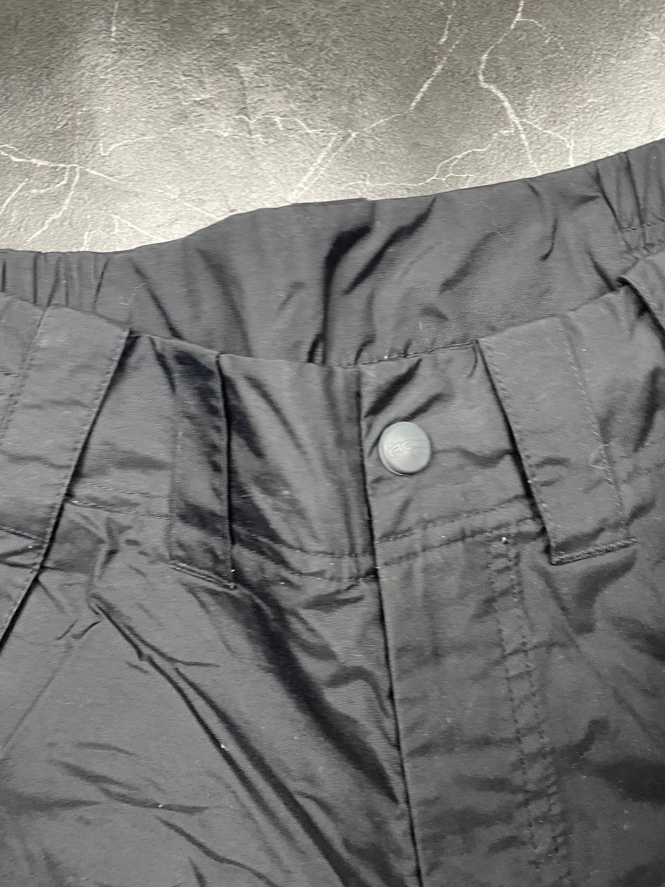Nike black ski trousers with ACG branding, button closure, and elasticated waistband.