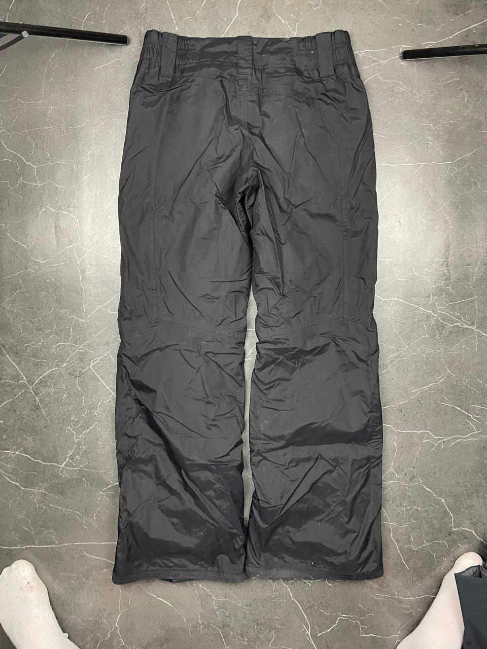Nike black ski trousers with ACG branding, button closure, and elasticated waistband.
