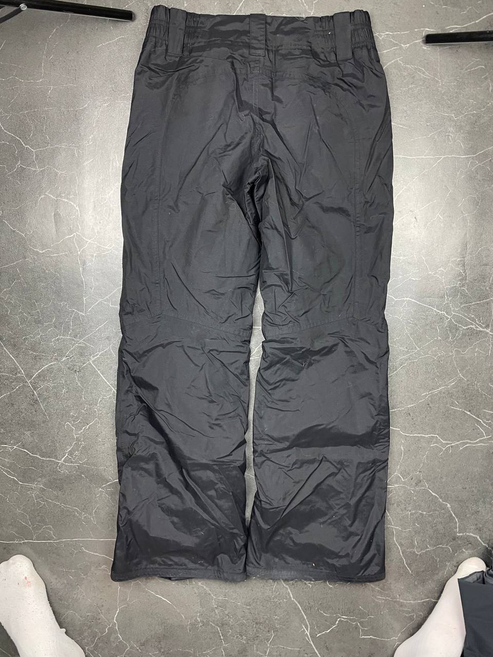 Nike black ski trousers with ACG branding, button closure, and elasticated waistband.