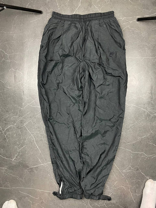 Nike black track pants with elastic waistband, side pockets, and ankle snaps.
